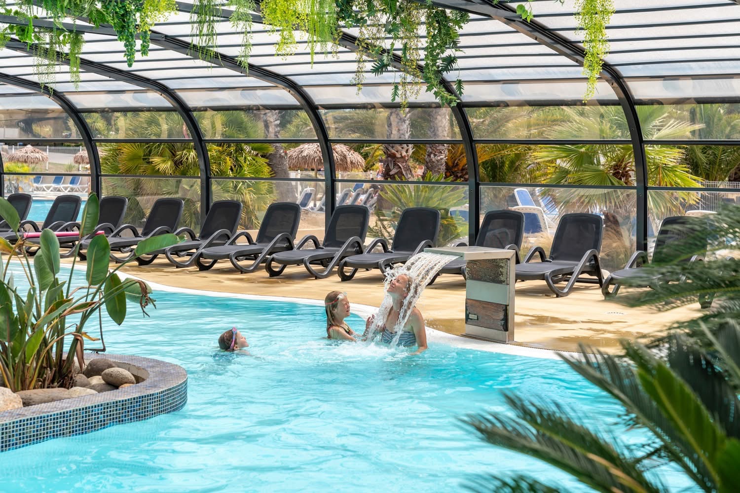 Vue intérieure d’un abri collectif : piscine et espace détente sous une structure vitrée